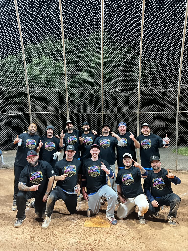 The Boathouse Beers team posing together on the softball field in black jerseys